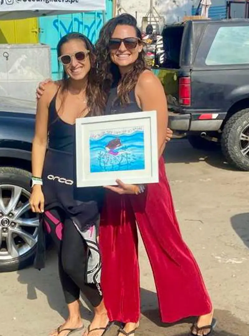 Tita y Eri con una de las ilustraciones enmarcada.