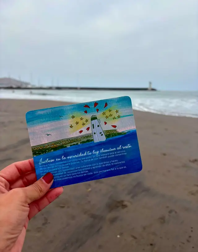 Una carta de la Cajita de Mar en la mano, frente al mar.