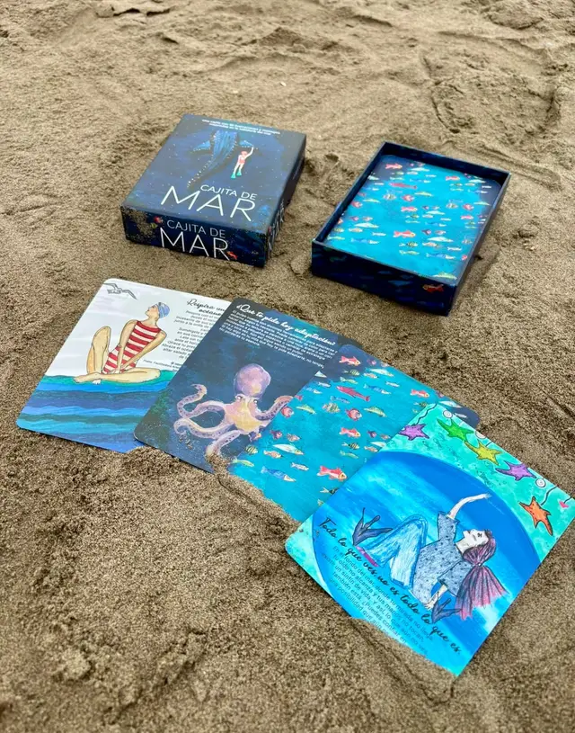 La Cajita de Mar abierta en la arena, con sus cartas extendidas junto al mar.